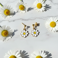 Gänseblümchen-Ohrstecker auf Marmor mit frischen Blumen
